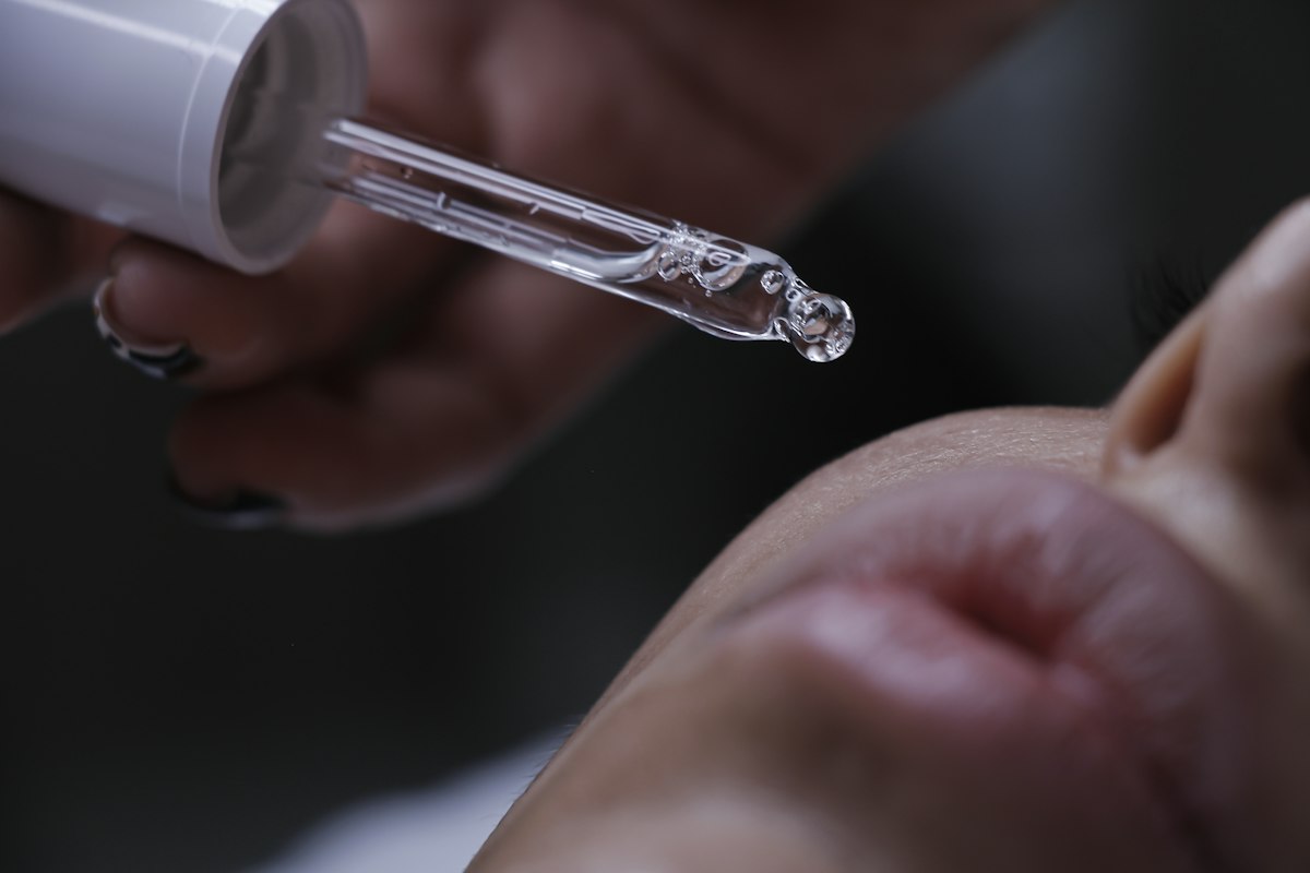 Serum wird mit einer Pipette bei einer Skincare-Behandlung aufgetragen