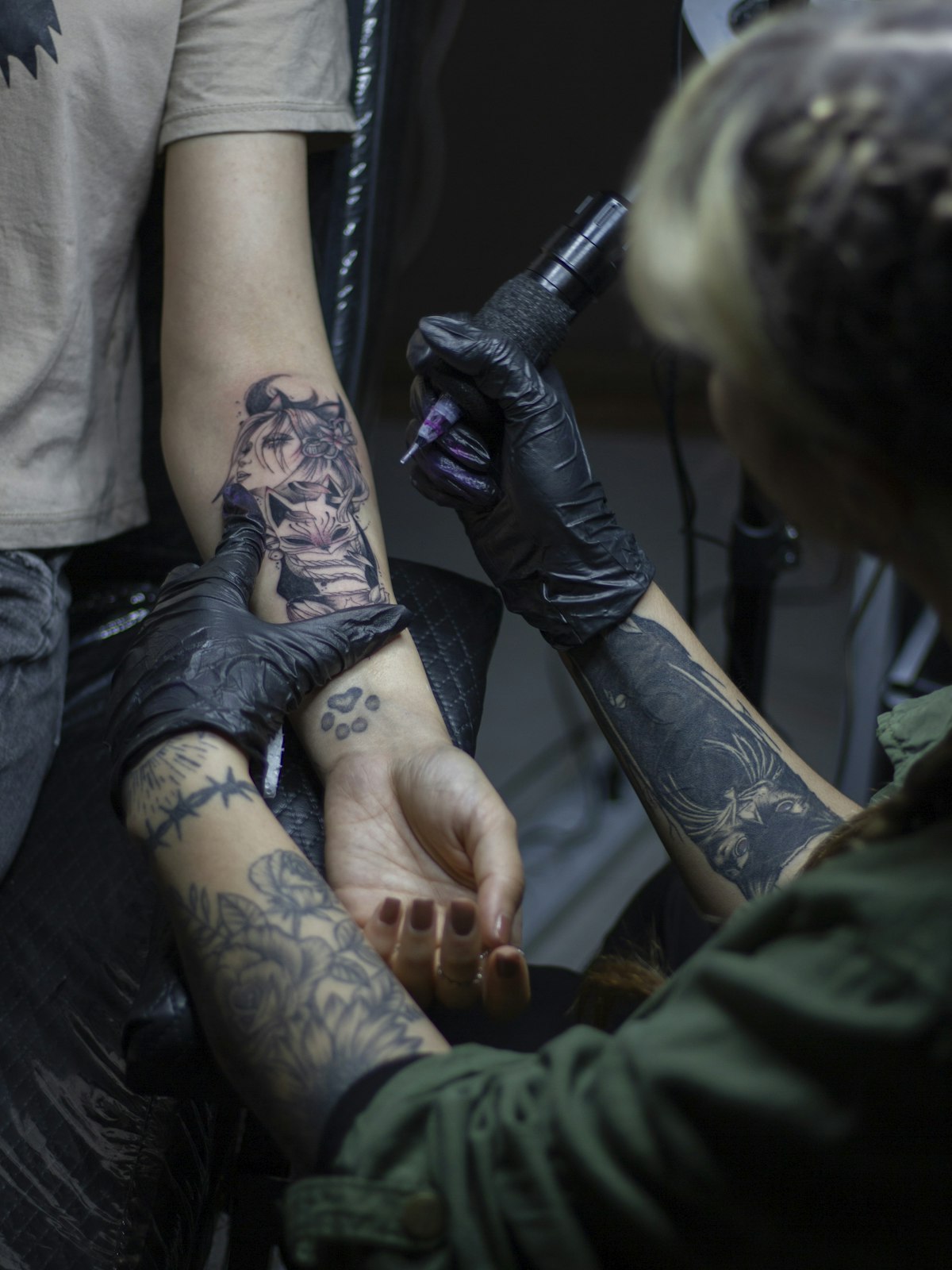 Tattoo-Artist bei der Arbeit an einem tätowierten Unterarm